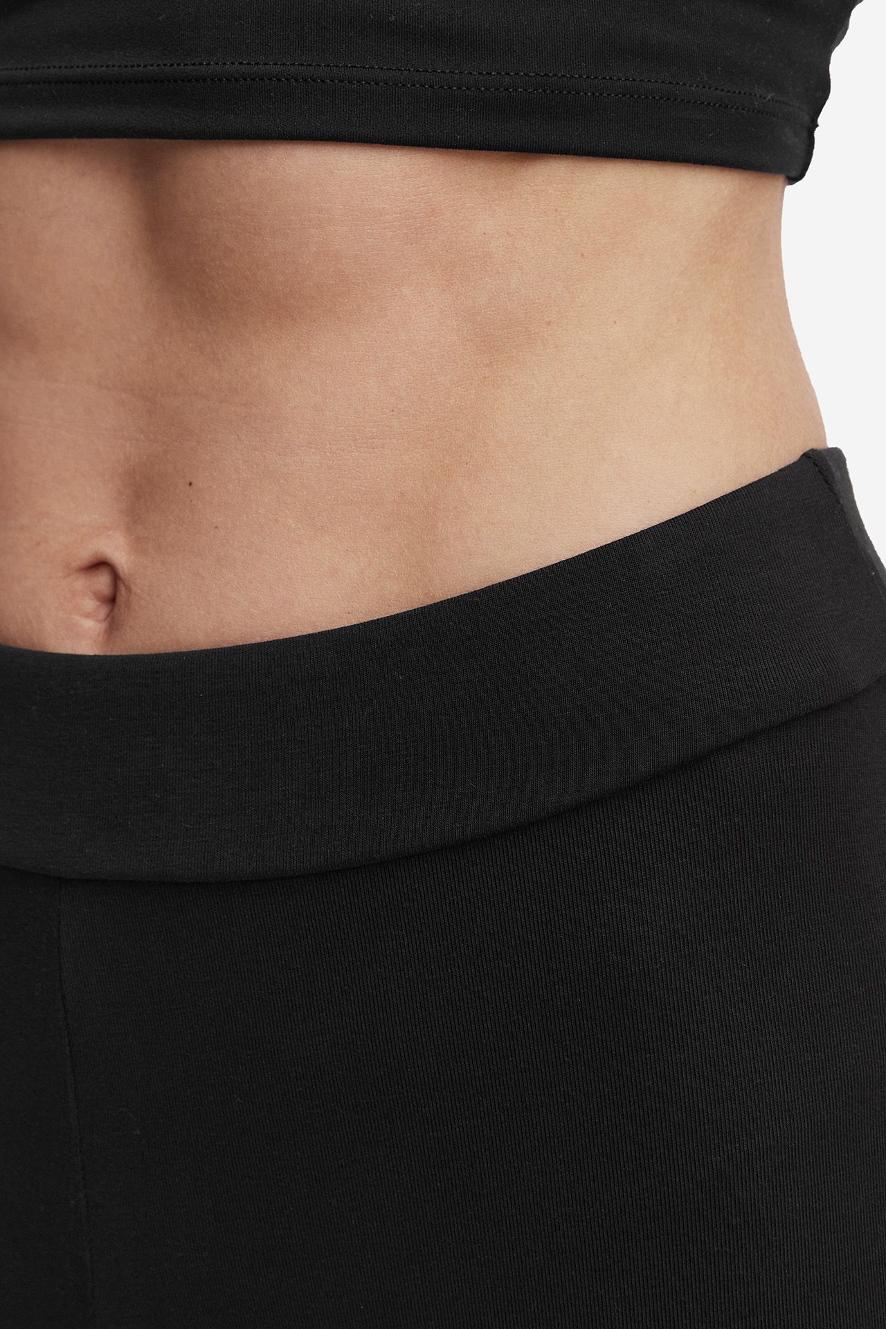 Zbliżenie na górną część legginsów sportowych i okolice pasa modelki.