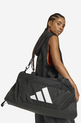 Modelka prezentująca sportową torbę na ramieniu, ujęcie sylwetki z boku.