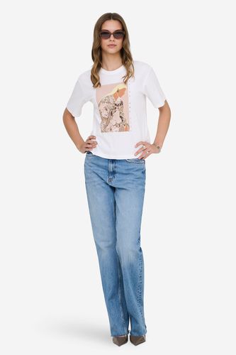 Modelka w T-shircie z nadrukiem i jeansach, ujęcie całej sylwetki od przodu.
