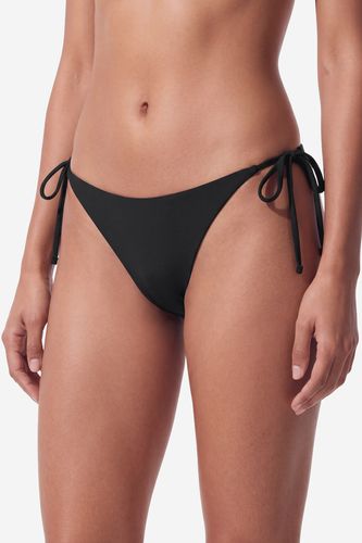 Modelka w majtkach bikini, ujęcie sylwetki od brzucha do ud z przodu.