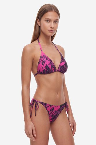 Modelka w komplecie bikini, ujęcie sylwetki pod kątem od przodu.