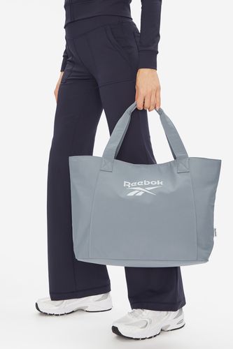 Modelka prezentująca torbę shopper trzymaną w dłoni, uchwyty do góry.