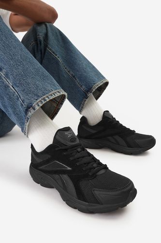 Model siedzący, but sportowy na stopie pokazany pod kątem z przodu.