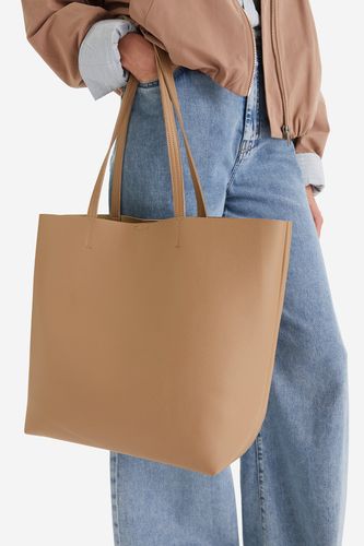 Modelka prezentująca dużą torebkę shopper trzymaną w dłoni.