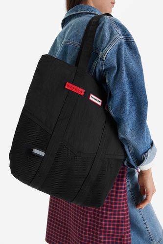 Modelka prezentująca torebkę shopper na ramieniu, widok z boku sylwetki.
