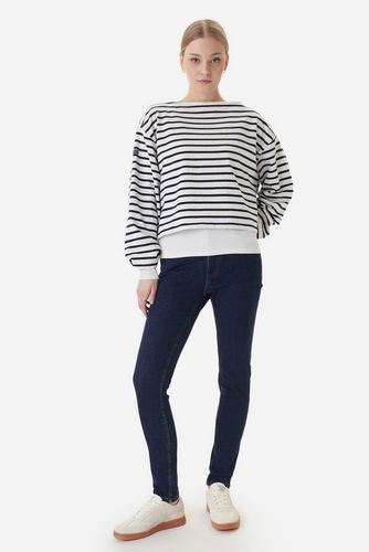 Modelka stojąca przodem, prezentuje spodnie w stylizacji z bluzą.