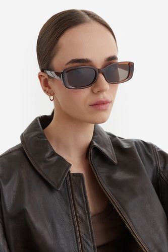 Modelka ubrana w okulary przeciwsłoneczne, ujęcie portretowe z przodu.
