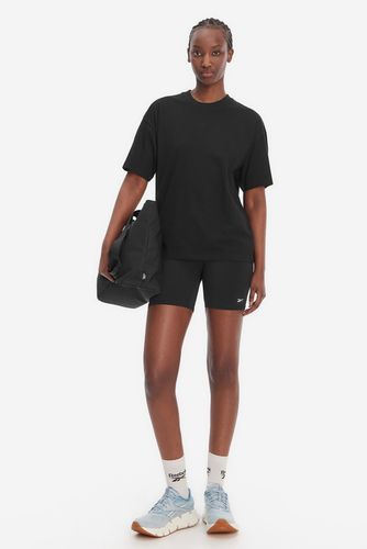 Modelka stojąca przodem, prezentuje koszulkę, szorty i sportowe buty.