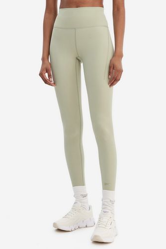 Modelka w legginsach sportowych, ujęcie sylwetki od przodu, od pasa w dół.