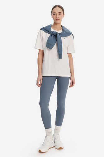 Modelka w legginsach, ujęcie całej sylwetki stojącej z przodu.