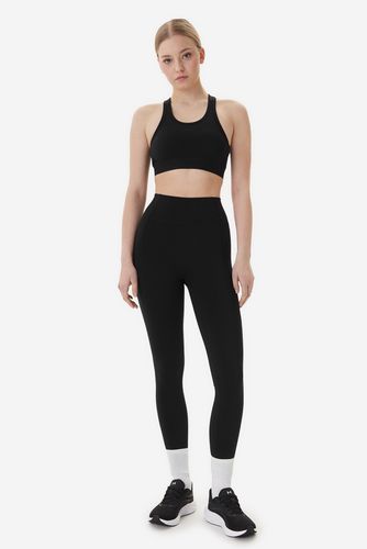 Modelka w legginsach sportowych, ujęcie całej sylwetki od przodu.