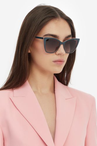 Modelka w półprofilu prezentująca okulary przeciwsłoneczne na twarzy.