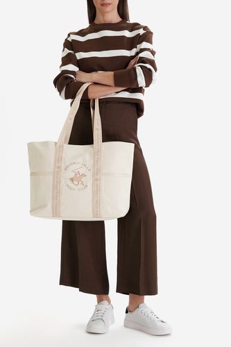 Modelka stojąca, prezentująca dużą torbę shopper zawieszoną na ramieniu.