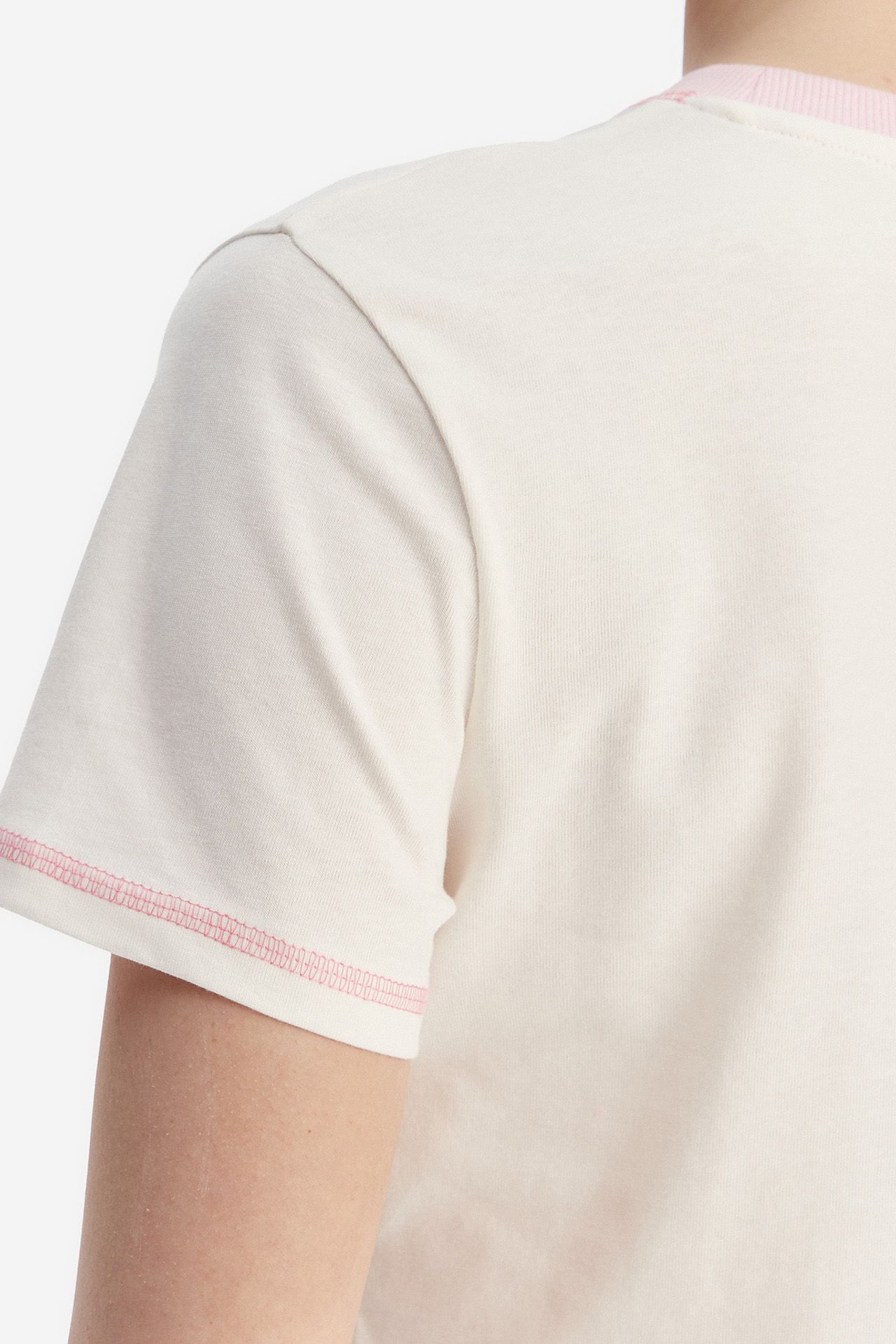Zbliżenie na górną część pleców modelki w T-shircie.