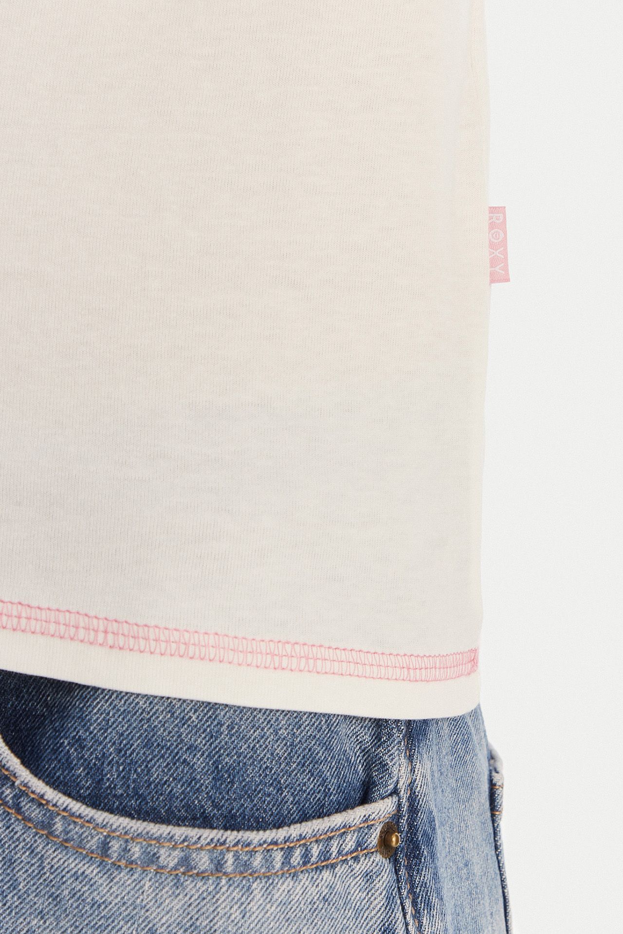 Zbliżenie na dół T-shirtu na modelce w dżinsach.
