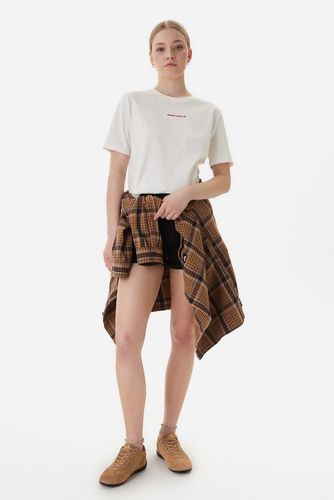 Modelka w pełnej sylwetce, T-shirt, szorty i koszula przewiązana wokół bioder.
