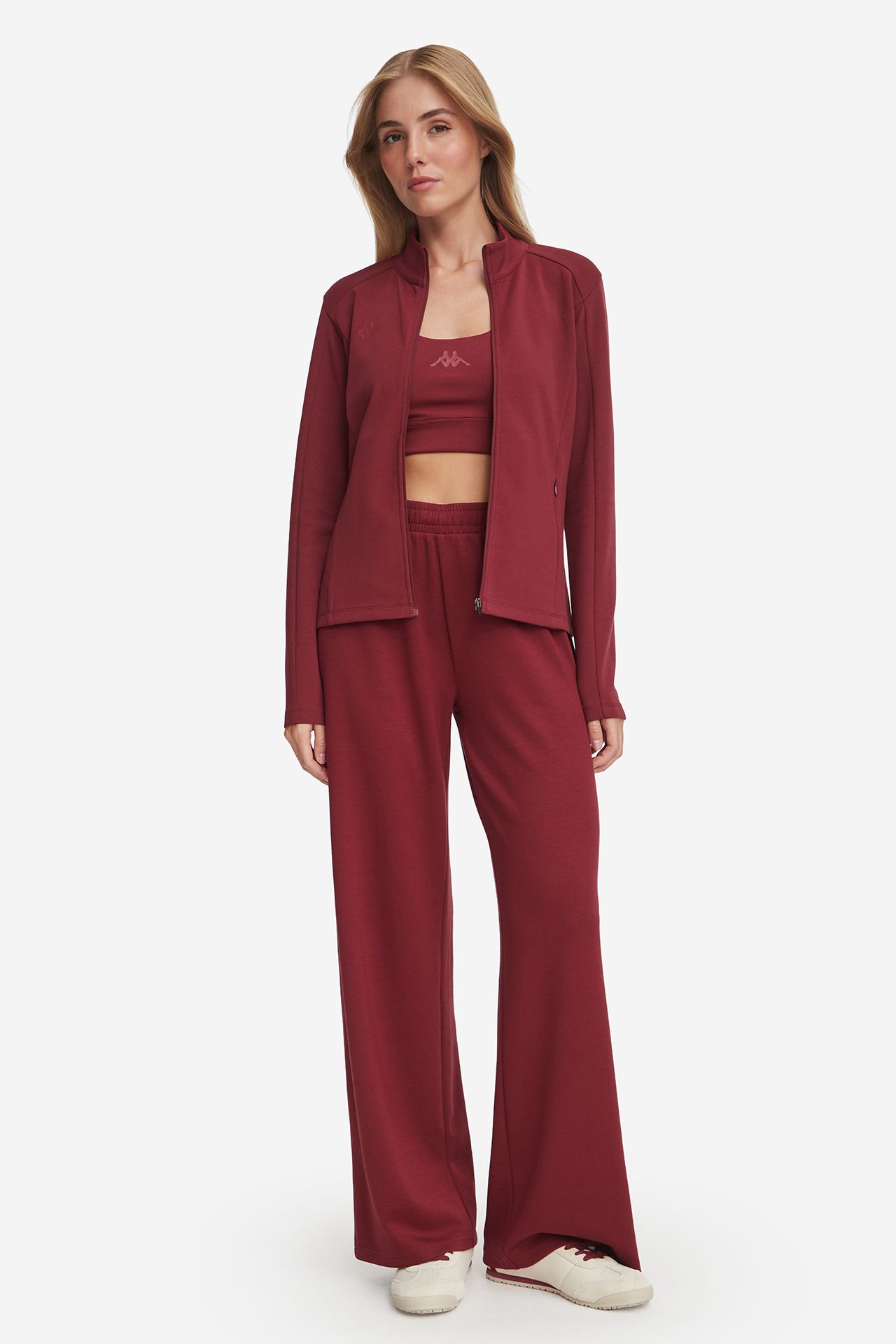 Modelka w komplecie sportowym, rozpięta bluza, widok całej sylwetki z przodu.
